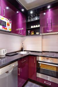 uma cozinha com armários roxos e um lavatório em Marina Apartment em Belgrado