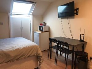 a bedroom with a bed and a table and a microwave at WIllesden Lodge Guest House in London