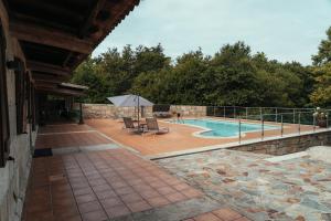 a patio with a pool and chairs and an umbrella at Casa Vacacional en Vilagarcía de Arousa in Vilagarcia de Arousa