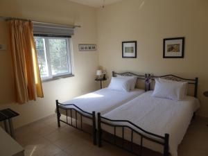 a bedroom with two beds with white sheets and a window at Elafonisi Vacation Blue Apartment in Agios Padeleimon