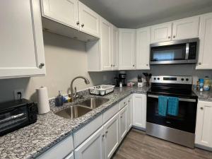 a kitchen with white cabinets and a sink and a stove at * Durham Diggs * Pet Friendly * King Bed * in Durham