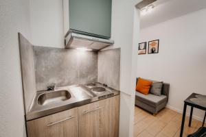 uma cozinha com um lavatório e um sofá num quarto em City Penzion em Košice
