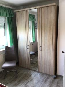 espejo en una habitación con silla y una habitación con cortinas verdes en Nordseekrabbe Bollmann en Carolinensiel