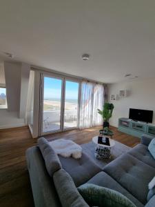 - un salon avec un canapé et une grande fenêtre dans l'établissement Penthouse Windkracht 10 aan het strand van Cadzand, à Cadzand