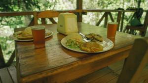 Doradal的住宿－El Tigrillo Rio Claro by Los Colores Ecoparque，一张木桌,上面放着两盘食物和两杯啤酒