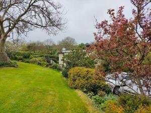 een tuin met bomen en struiken en een huis bij Broadhaven Cottage, Freshwater East, Pembs in Pembroke