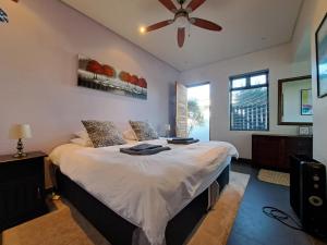a bedroom with a large bed with a ceiling fan at Domaine Coutelier in Stellenbosch