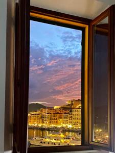 a window with a view of a city and a boat at Le Stanze sul Mare in Portoferraio