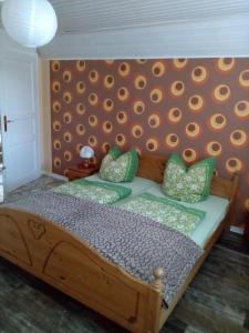 a bedroom with a wooden bed with green pillows at Urlaub auf dem Ferienhof in Berumbur