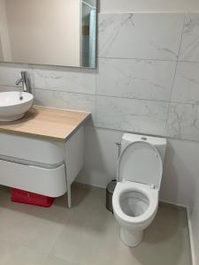 a bathroom with a white toilet and a sink at maison 3 pièces in Pierrelaye