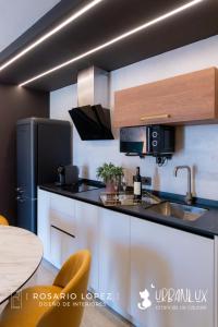 a kitchen with white cabinets and a black refrigerator at Urbanlux Olimpia Sleep & Park in Albacete