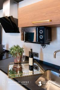 a kitchen with a microwave and two glasses of wine at Urbanlux Olimpia Sleep & Park in Albacete