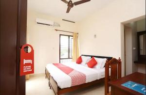 a bedroom with a bed with red pillows and a window at Hotel Sunday - Townhouse Club Airport Trivandrum in Trivandrum
