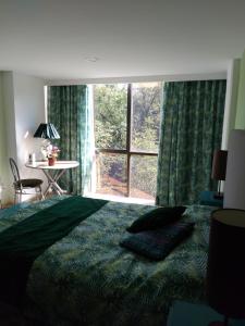 1 dormitorio con cama y ventana grande en Charming bedroom overlooking beautiful trees in the best Condesa Area, en Ciudad de México