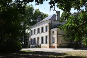 um velho edifício de pedra com árvores em frente em Chateau Morinerie 