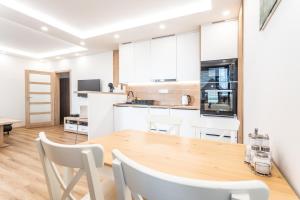 a kitchen and dining room with a wooden table and chairs at SCANDIC Apartments Plešivec in Abertamy