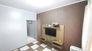un salon avec une télévision sur un mur dans l'établissement Casa Bethel - De 3 a 5 minutos do Thermas, à Olímpia
