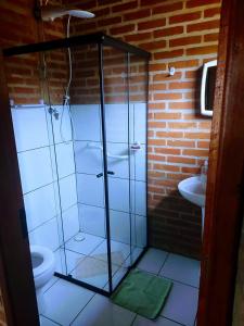 a bathroom with a glass shower with a toilet and a sink at Tocas do Lago in São Bento do Sapucaí