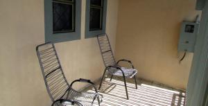 2 chaises assises sur une terrasse couverte à côté d'une fenêtre dans l'établissement Casa Bethel - De 3 a 5 minutos do Thermas, à Olímpia
