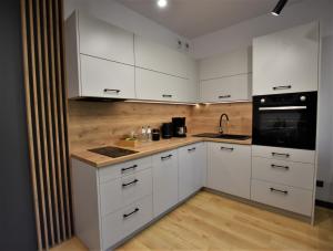 una cucina con armadietti bianchi ed elettrodomestici neri di Green Apartament City Center a Breslavia