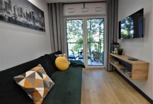 un soggiorno con divano verde e porta scorrevole in vetro di Green Apartament City Center a Breslavia