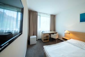a hotel room with a bed and a desk and a television at Hotel Ehrlich Prague in Prague