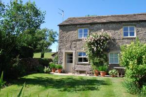 a stone cottage with a bench in the yard at The Nook Bank Newton in Bell Busk