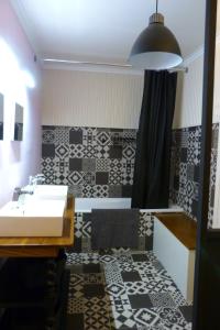 a bathroom with a sink and black and white tiles at Le Clos Notre Dame B&B in Mareuil