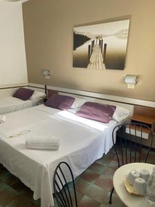 a room with two beds and a table with chairs at Hotel Cappello in Cesena