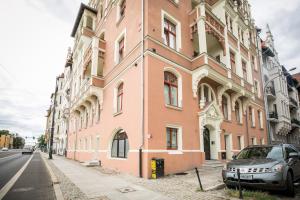 a pink building with a car parked in front of it at Apartament Migdałowy in Toruń