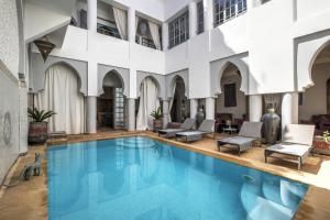 una piscina cubierta en un edificio con sillas y mesas en Riad Shemsi en Marrakech