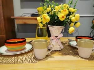 uma mesa com copos e um vaso de flores amarelas em Lovely Studio 1 Bedroom Apartment, Olongapo City Centre em Olongapo
