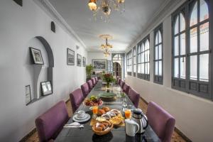 a long dining room with a long table and purple chairs at Riad Shemsi in Marrakesh