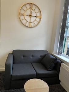 a living room with a couch and a clock on the wall at Bv Comfy Budget Studio At Quebec Street Bradford in Bradford