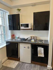 een kleine keuken met een wastafel en een magnetron bij Bv Comfy Budget Studio At Quebec Street Bradford in Bradford