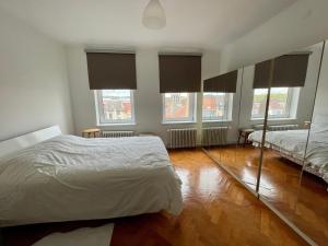 1 Schlafzimmer mit 2 Betten, Fenstern und Holzböden in der Unterkunft Superbe appartement DUPLEX avec Jacuzzi in Brüssel