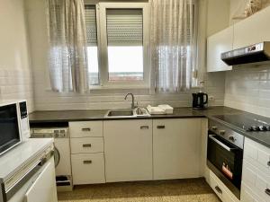 eine Küche mit weißen Schränken, einem Waschbecken und einem Fenster in der Unterkunft Superbe appartement DUPLEX avec Jacuzzi in Brüssel