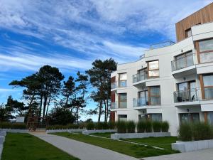 um edifício de apartamentos branco com árvores ao fundo em Apartament w Let's Sea Baltic Park em Gąski