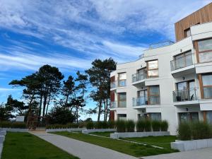 a white apartment building with trees in the background at Apartament w Let's Sea Baltic Park in Gąski