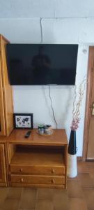 uma televisão de ecrã plano numa parede com uma cómoda de madeira em Apartamento MontEsquiBonito Bonito Apartamento en Yésero em Yésero
