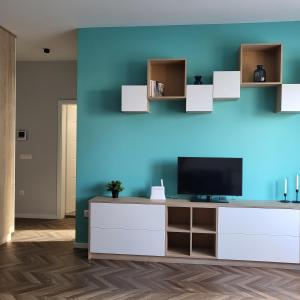 a living room with a television on a blue wall at New luxury apartment next to subway with garage in Sofia