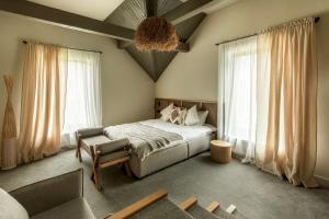 a bedroom with a bed and a chair and windows at Poderey Villas in Yaremche