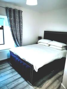 Una cama con sábanas blancas y almohadas en un dormitorio en Elmwood House Luxury Seaview Accommodation, en Donegal