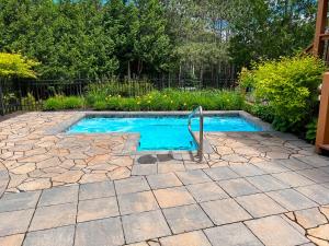 a swimming pool in a yard with a stone patio at Le Beachside by Gestion ELITE in Mont-Tremblant