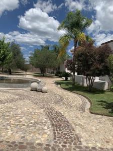 a stone walkway with a fountain and a palm tree at Villa Quinta Lomas casa completa con aéreas verdes in León