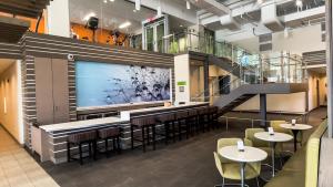 奥马哈EVEN Hotel Omaha Downtown - Old Market by IHG的带酒吧的餐厅，酒吧里有椅子和桌子