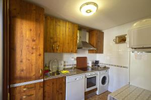uma cozinha com armários de madeira, um lavatório e uma máquina de lavar louça em Vivienda Rural LA SOÑADA en El Bosque em El Bosque