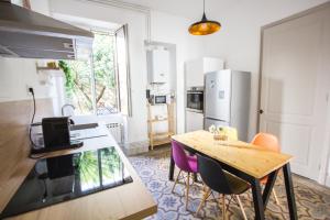 een keuken met een tafel en stoelen en een koelkast bij Le 62 - Spacieux T2 avec JARDIN, parking & tramway in Grenoble