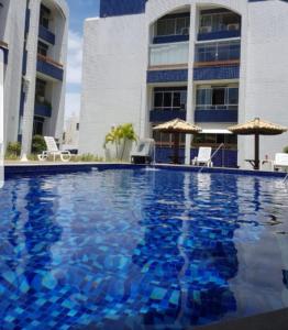 a large swimming pool in front of a building at Village Duplex, Vilas do Atlântico in Lauro de Freitas