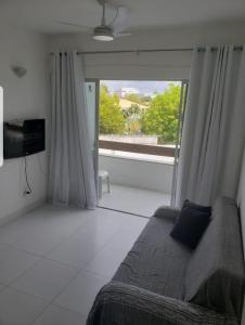 a living room with a couch and a large window at Village Duplex, Vilas do Atlântico in Lauro de Freitas +16 photos